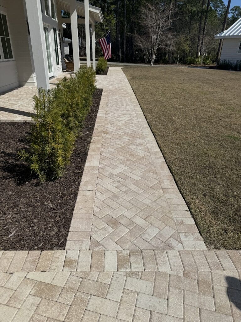 a brick walkway leading to a white house